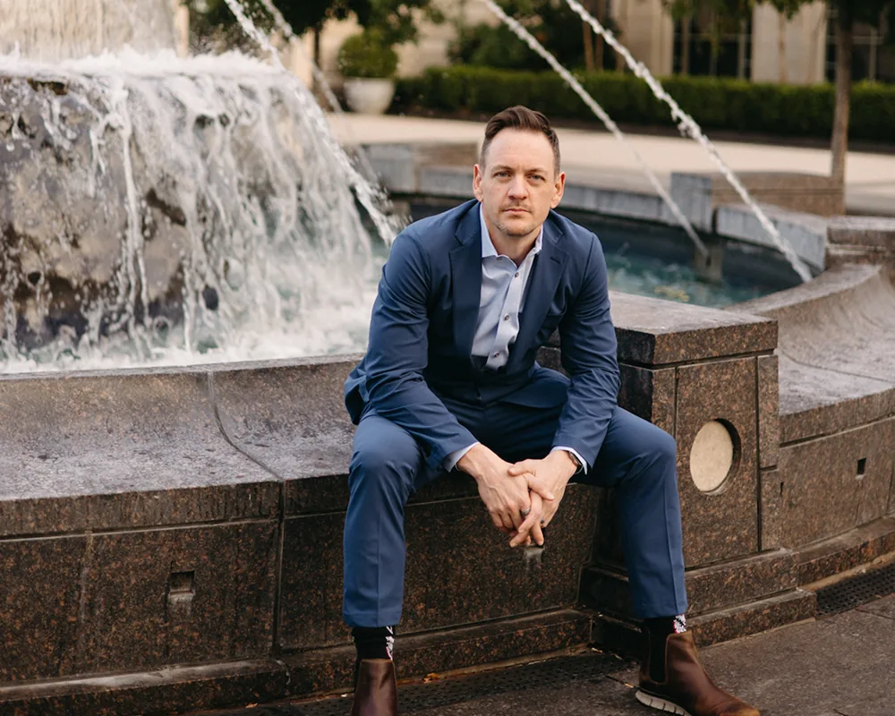Arron Bennett seated beside a city fountain